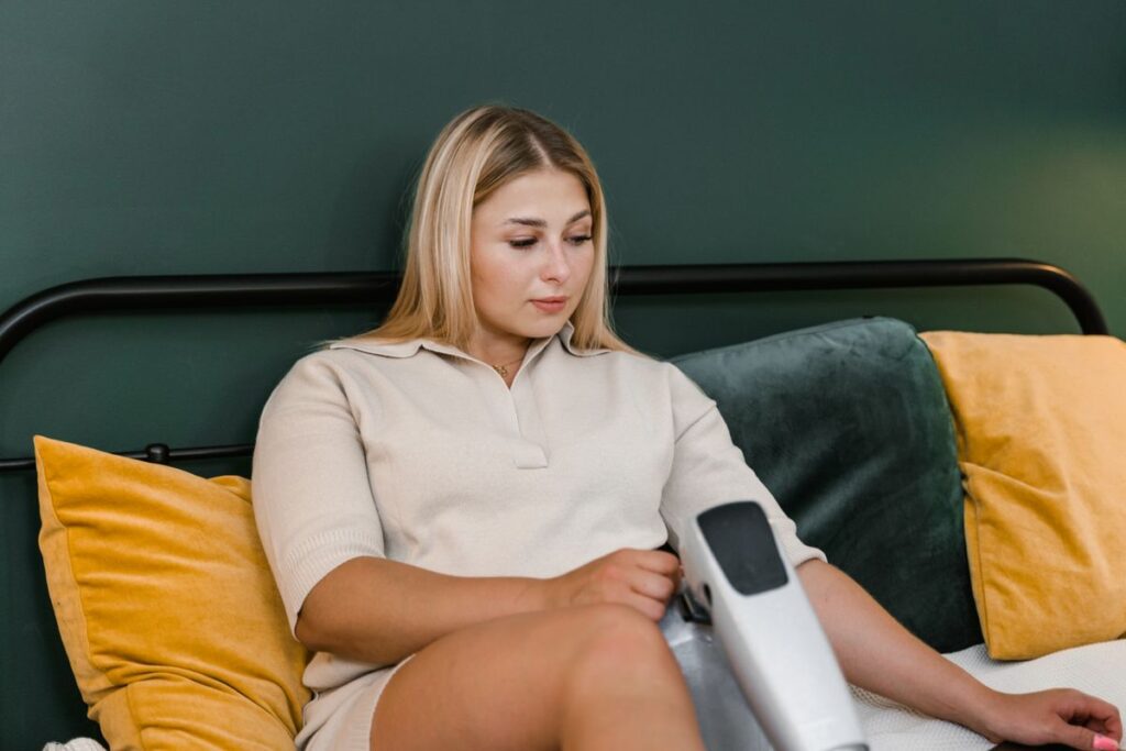 Woman using an at-home IPL hair removal device on the sofa, the home alternative to clinic laser