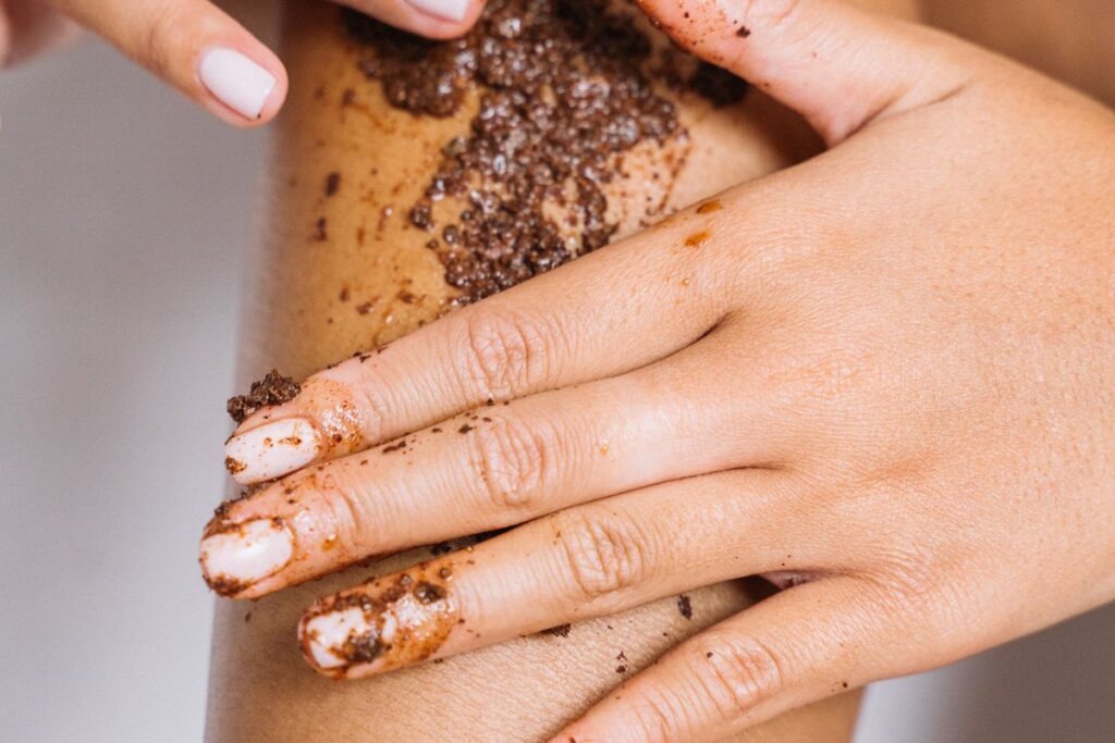 Close-up of hands applying an exfoliating body scrub to skin to help prevent ingrown pubic hair