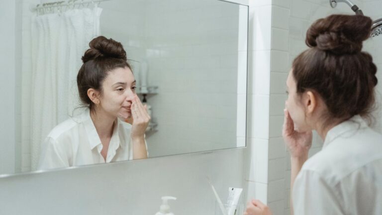 Woman preparing her skin at the bathroom mirror, illustrating how to prepare for IPL