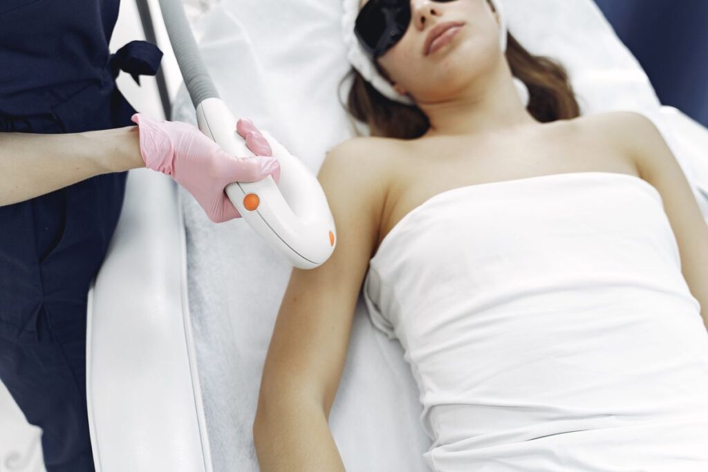 Technician in gloves operating professional laser hair removal equipment with contact cooling