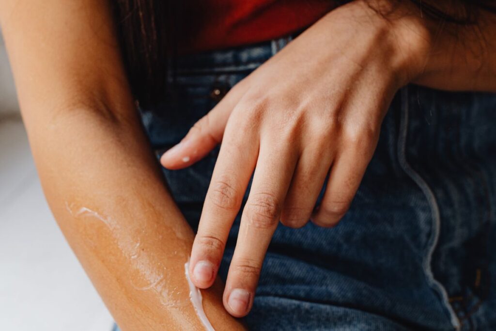 Fingers applying moisturiser to an arm to help smooth keratosis pilaris